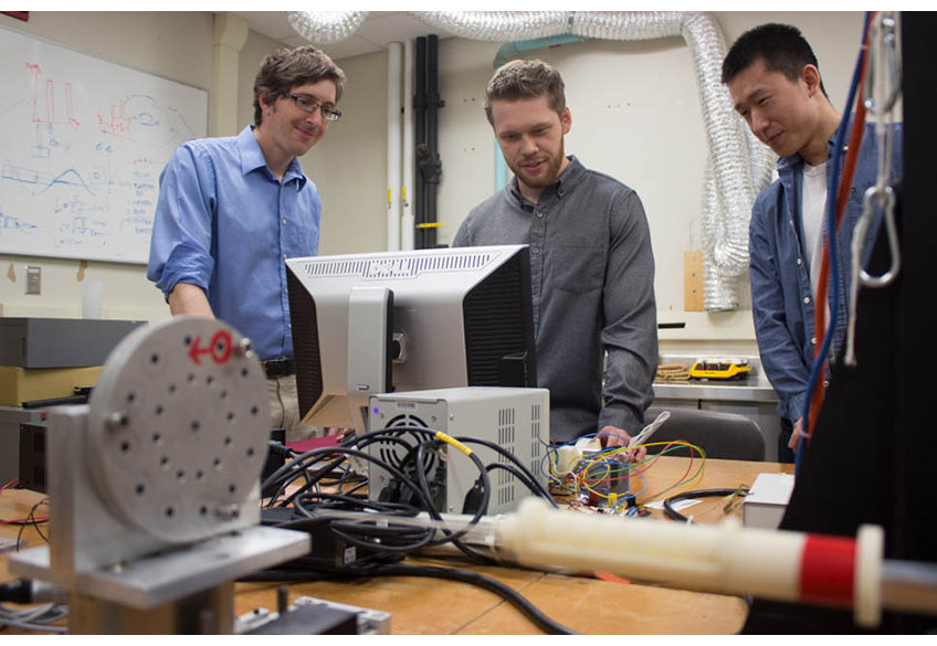  Jason Moore, associate professor of mechanical engineering, David Pepley, a doctoral student studying mechanical engineering, and Yichun (Leo) Tang, undergraduate student studying mechanical engineering work with the needle simulator training device.