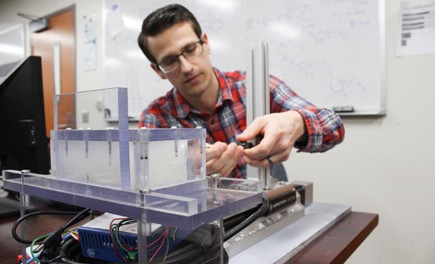 a man fine tunes a piece of equipment in a lab