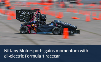 A Formula 1 racecar zooming past orange traffic cones